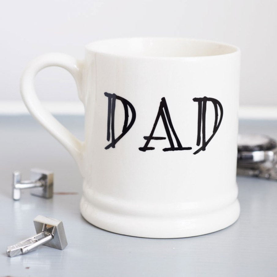 Ceramic Dad mug with black lettering, styled with silver cufflinks on a pale blue surface, a thoughtful gift for Dad from Sweet William Designs