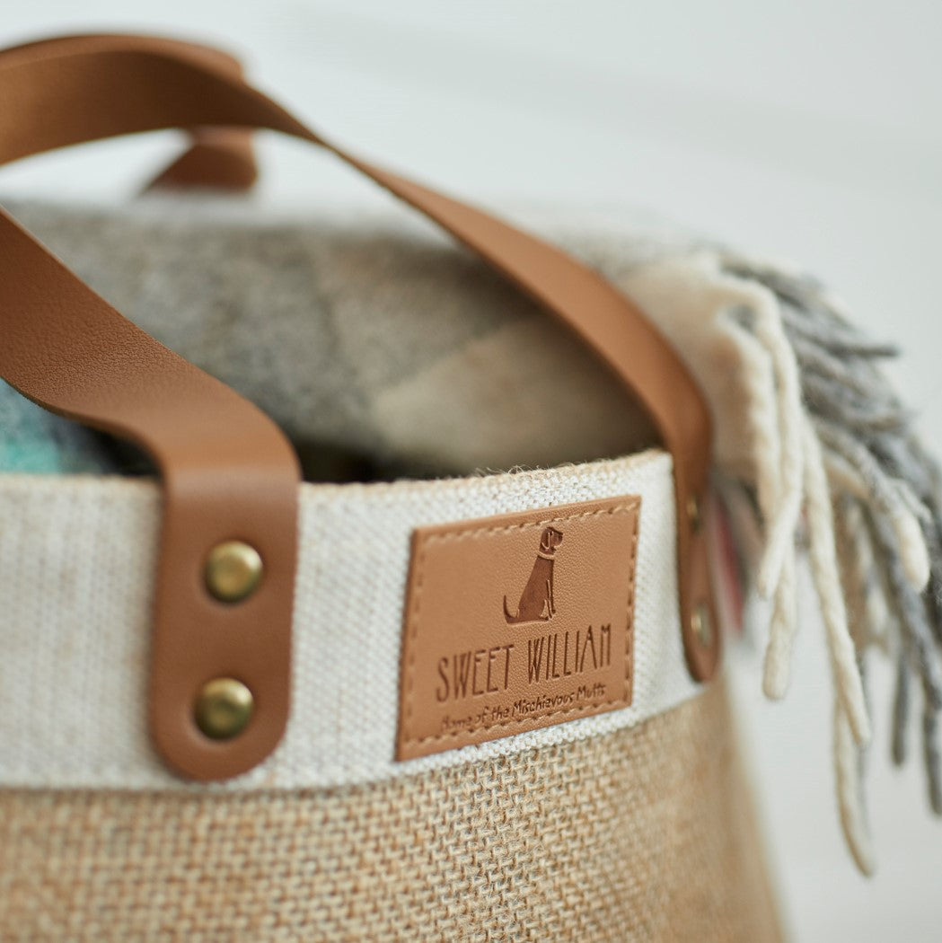 Close-up of Sweet William leather label on jute bag — branded leather patch with tan leather handles and brass rivets