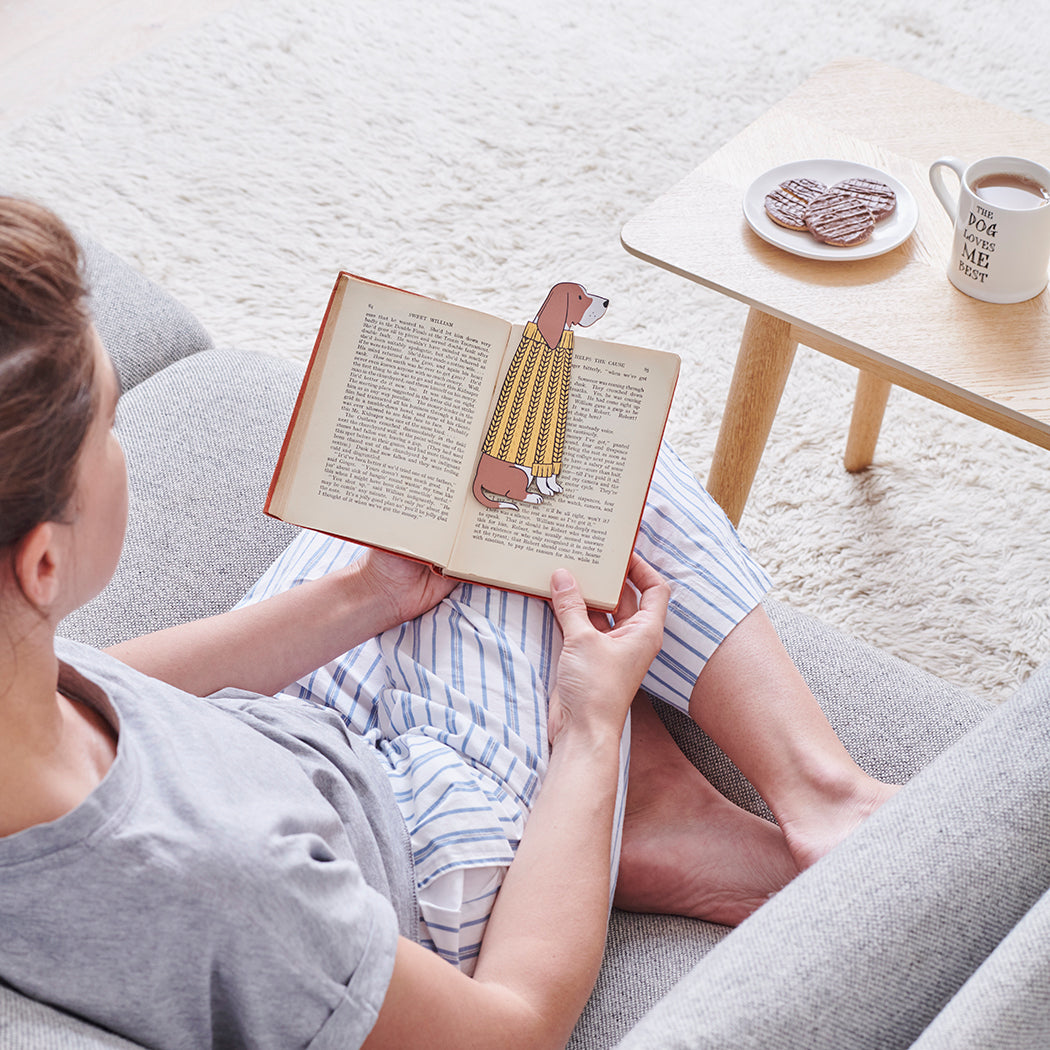 Woman reading a book with a Basset Hound bookmark and bestselling "The Dog Loves Me Best" mug by Sweet William Designs