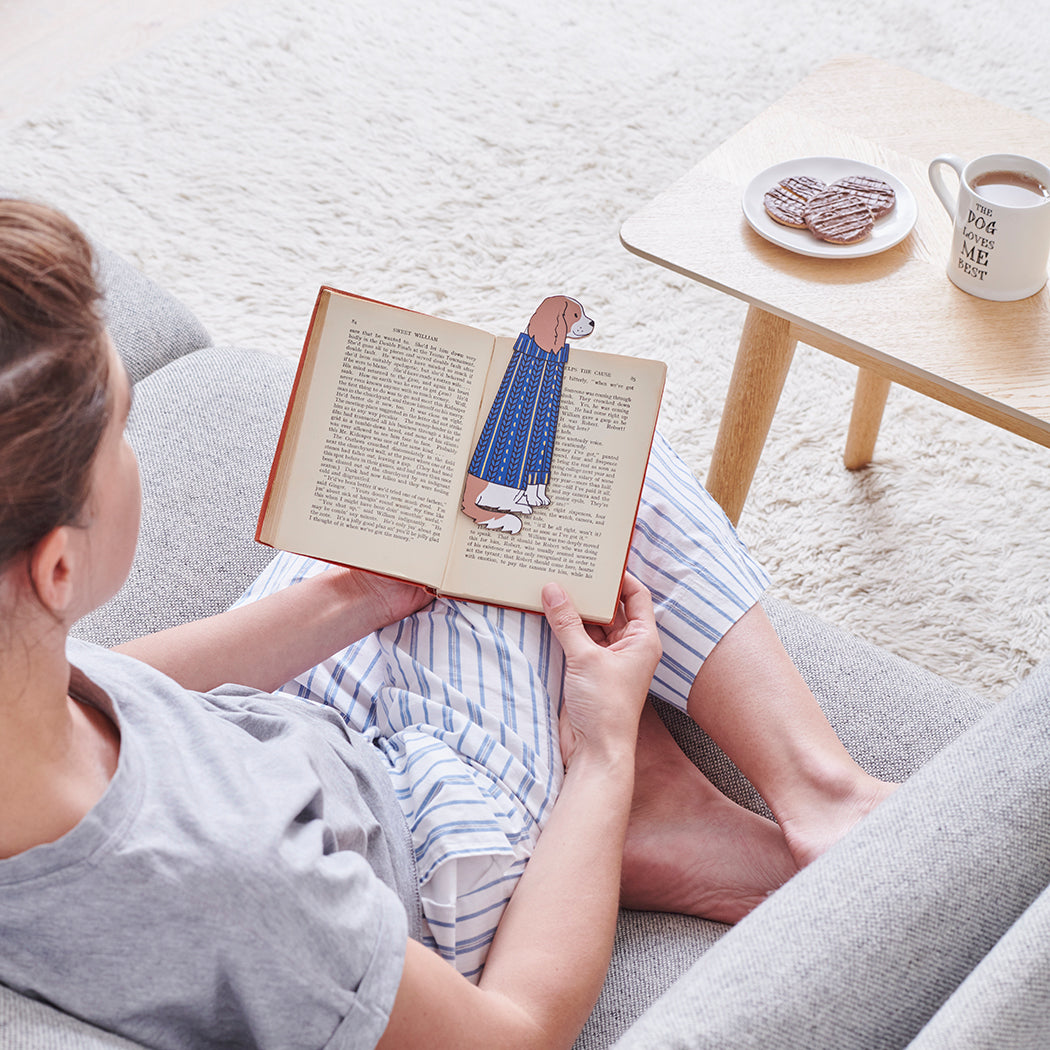 Woman reading a book with a Cavalier King Charles Spaniel bookmark and bestselling "The Dog Loves Me Best" mug by Sweet William Designs