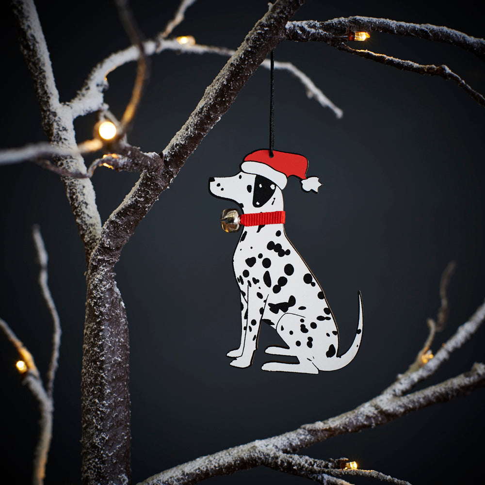 Dalmatian Christmas tree decoration hanging on lit winter tree — wooden dog decoration with Father Christmas hat and jingle bell collar by Sweet William Designs