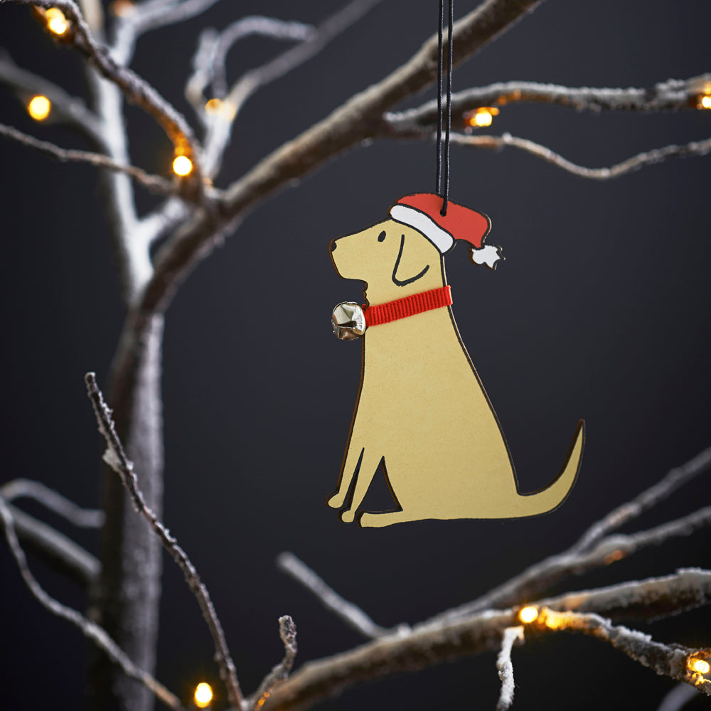 Yellow Labrador Christmas tree decoration hanging on lit winter tree — wooden dog decoration with Father Christmas hat and jingle bell collar by Sweet William Designs