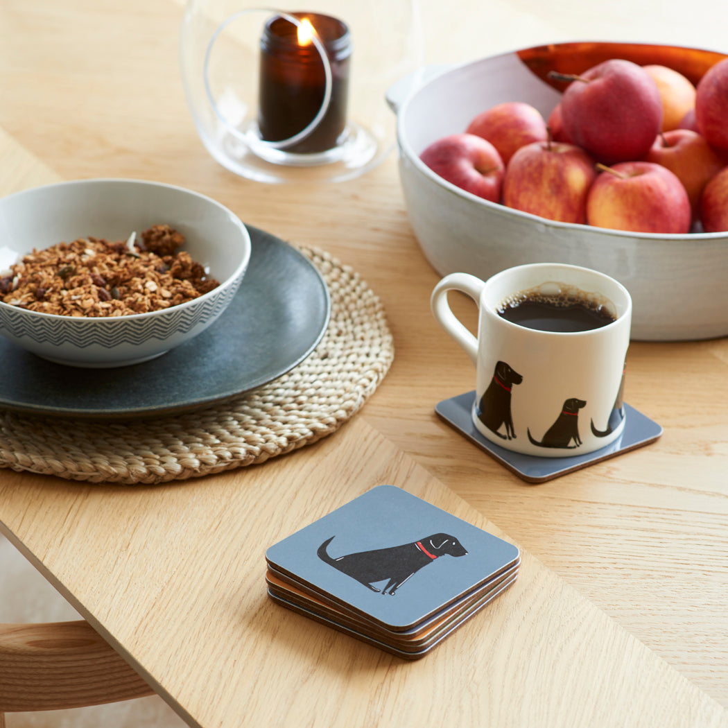 Black Labrador coasters stacked on a breakfast table beside a matching mug