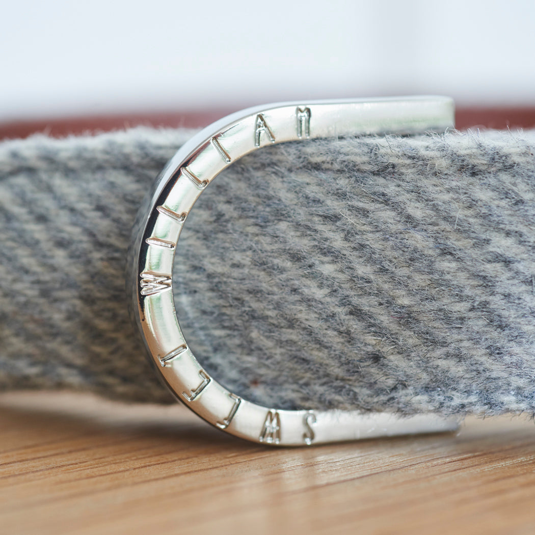 Close-up of the branded D-ring on a grey tweed dog collar