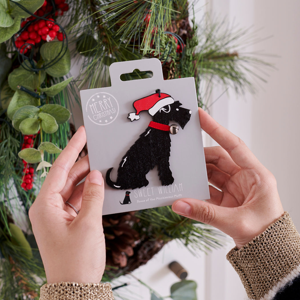 Black Schnauzer Christmas tree decoration held in hands on backing card — Father Christmas hat and jingle bell collar, dog lover gift by Sweet William Designs