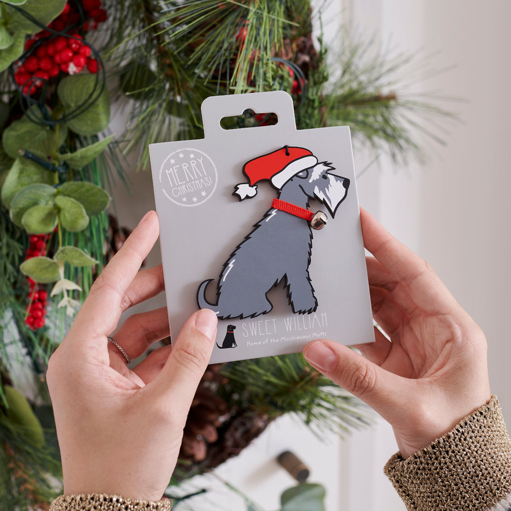 Grey Schnauzer Christmas tree decoration held in hands on backing card — Father Christmas hat and jingle bell collar, dog lover gift by Sweet William Designs