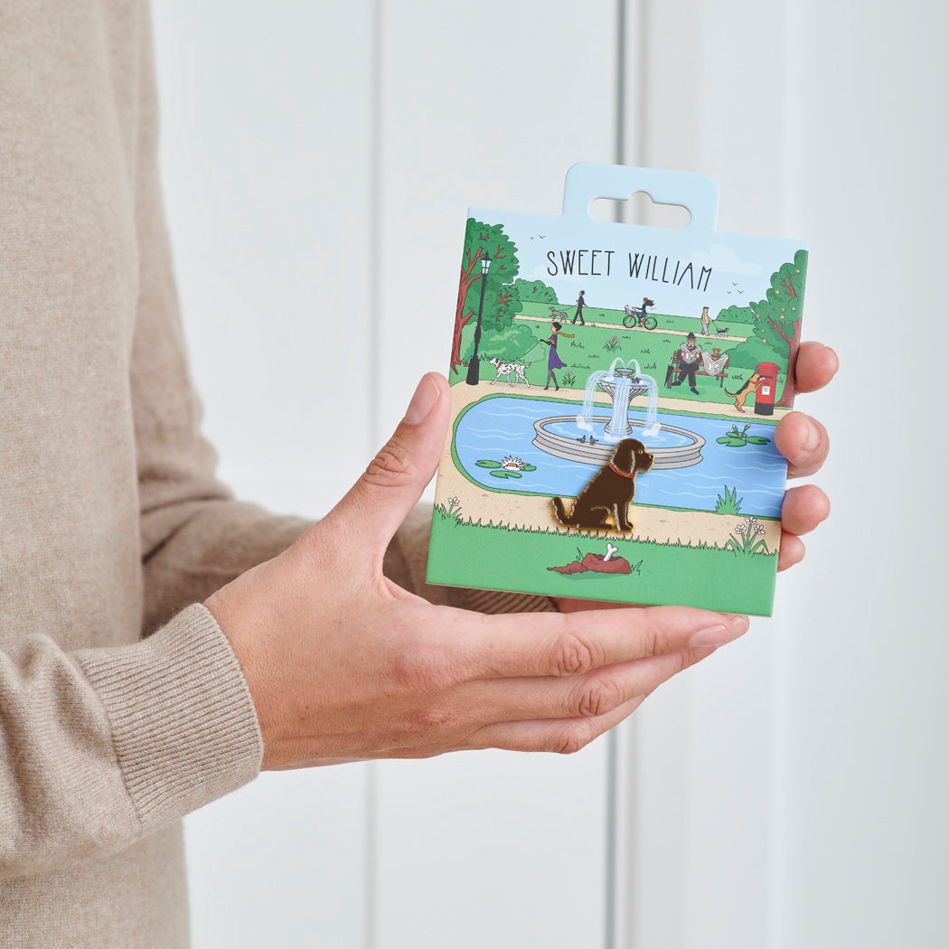 Chocolate Cockapoo / Labradoodle enamel dog pin held in hands on illustrated park backing card — gold-plated dog lover gift by Sweet William Designs