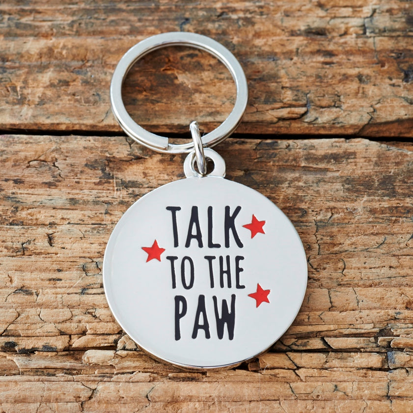 Close-up of 'Talk To The Paw' dog tag — silver-plated brass with red star design, personalised dog ID tag by Sweet William Designs
