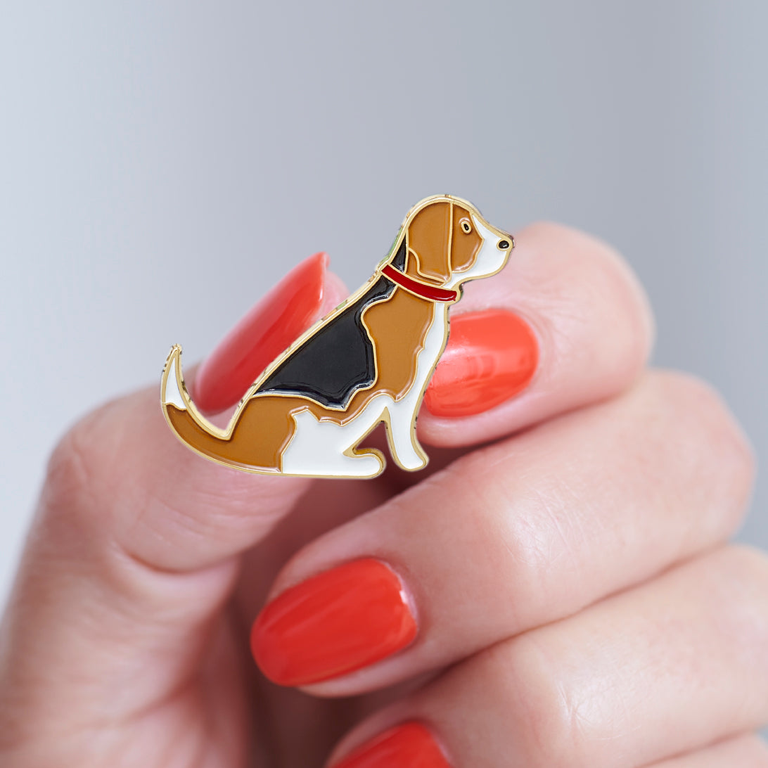 Close-up of a Beagle enamel pin held in hand, showing the detailed Beagle dog design by Sweet William Designs
