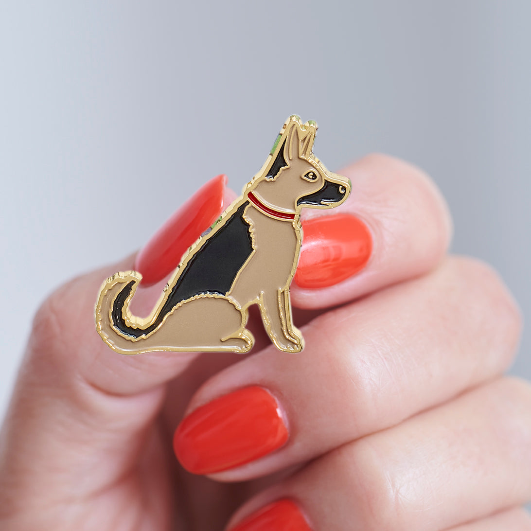 Close-up of a German Shepherd enamel pin held in hand, showing the detailed German Shepherd illustration by Sweet William Designs
