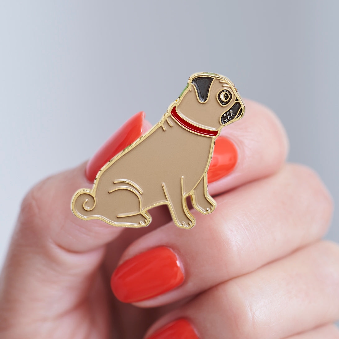 Close-up of a Pug enamel pin held in hand, showing the detailed Pug illustration by Sweet William Designs