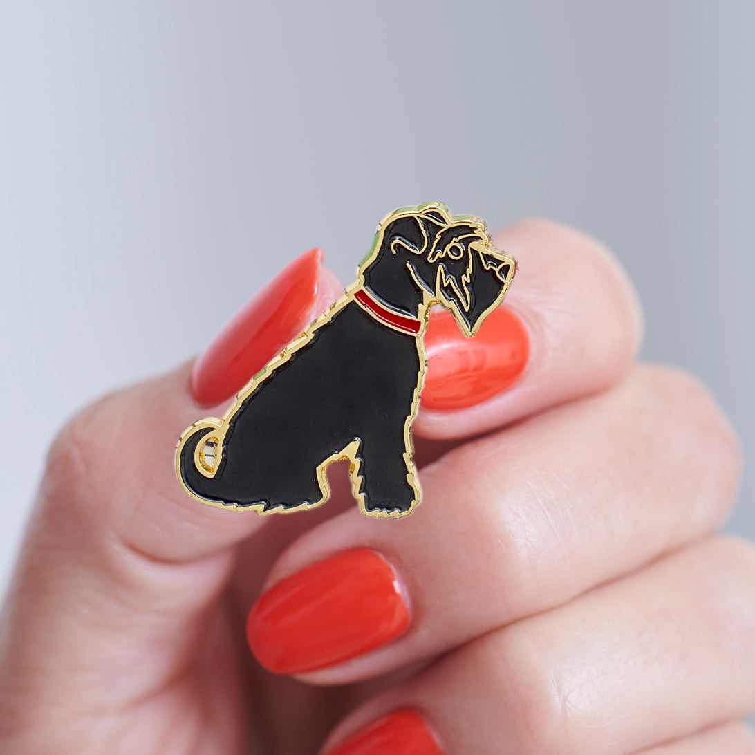 Close-up of a Black Schnauzer enamel pin held in hand, showing the detailed Schnauzer illustration by Sweet William Designs