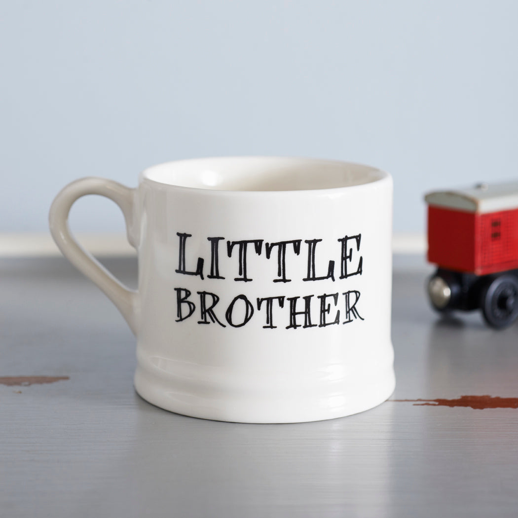 Ceramic “Little Brother” mug photographed beside a red toy train as a fun gift for a little brother