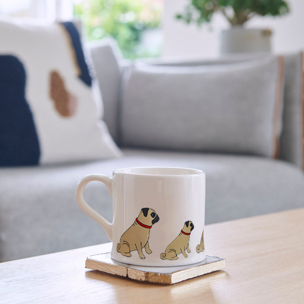 Sweet William Pug Mug on a coffee table — illustrated Pug repeat pattern ceramic mug