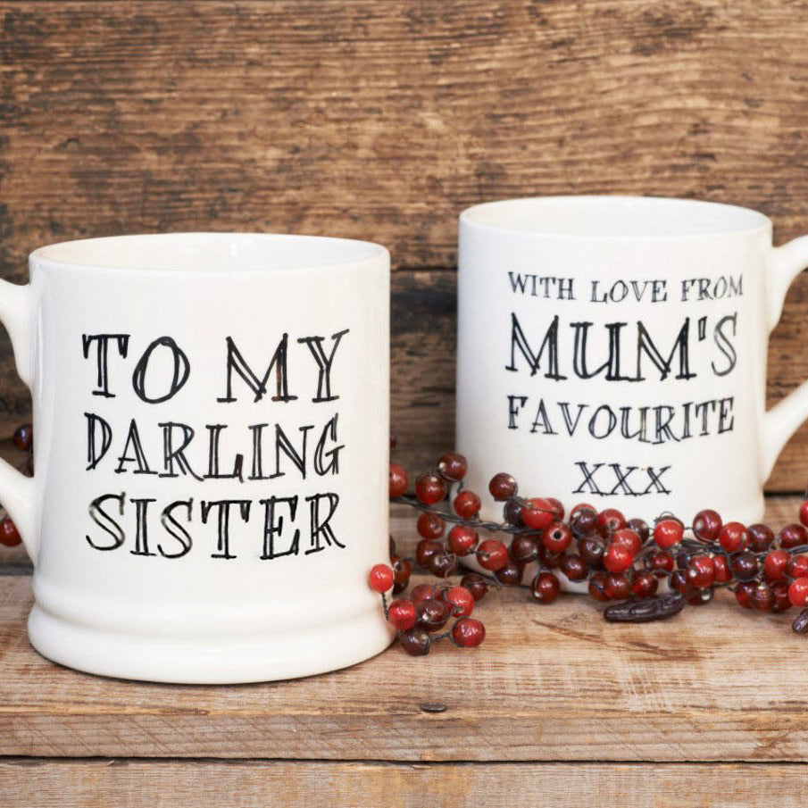 Ceramic Darling Sister mug showing the affectionate front message and cheeky reverse message, styled with red berries on a rustic wooden background