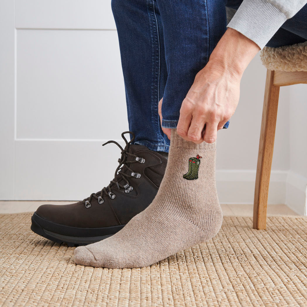 Man wearing wellies gardening socks indoors — soft taupe marl wool blend socks with embroidered green wellies and robin, gardening gift by Sweet William Designs