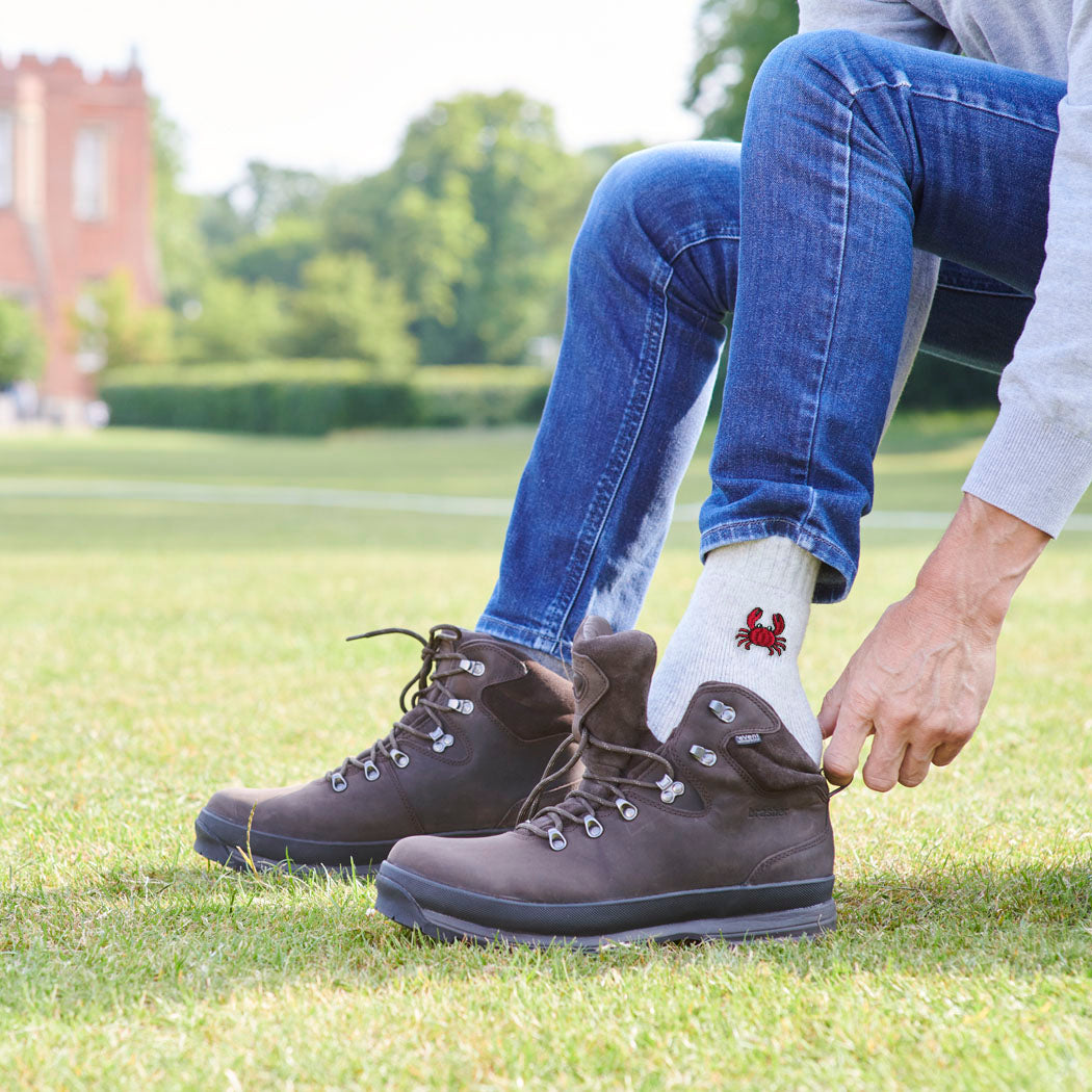 Man lacing up walking boots wearing crab wool socks outdoors — unisex wool blend socks, one size fits UK 3–12, coastal gift