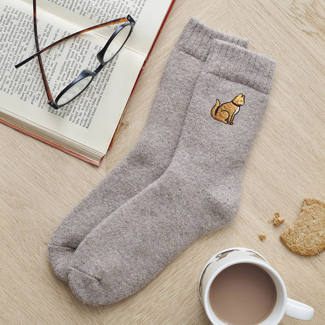 Ginger cat embroidered wool socks laid flat with book, glasses and cup of tea — cosy cat lover gift by Sweet William Designs
