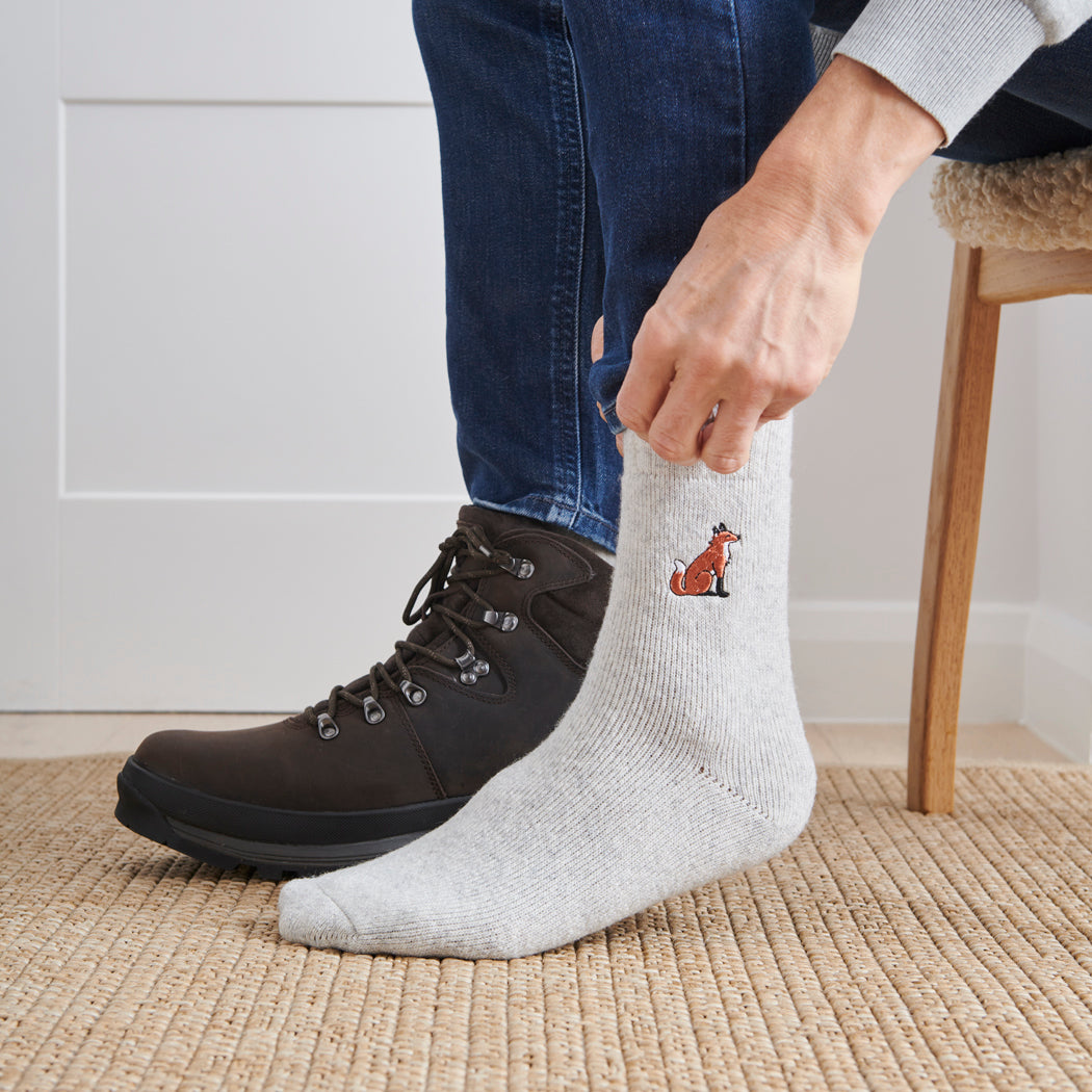 Man pulling on fox wool socks with walking boots indoors — unisex embroidered wool blend socks by Sweet William Designs