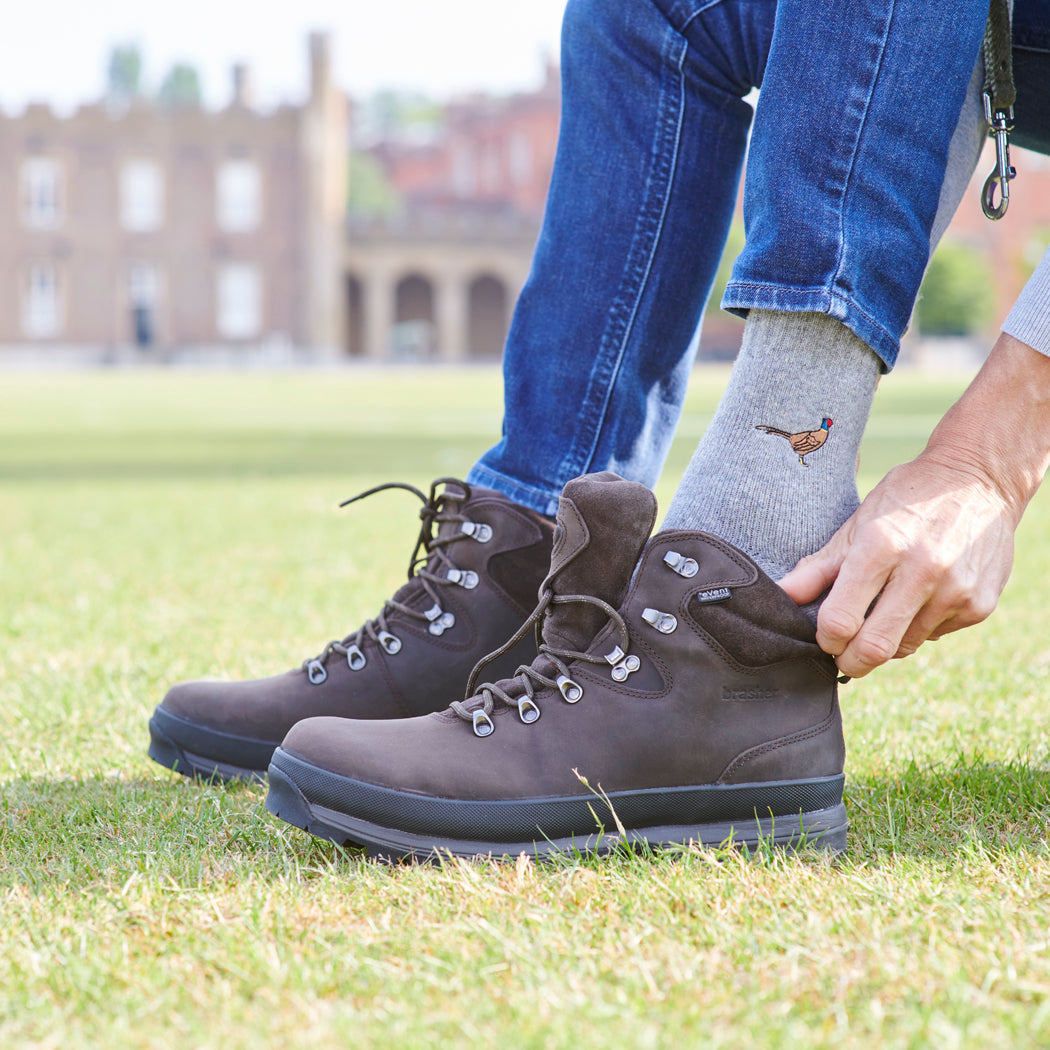 Man wearing embroidered pheasant wool socks with walking boots outdoors — countryside-inspired socks, a thoughtful gift for nature lovers