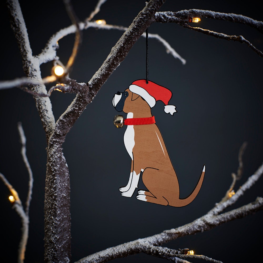 Boxer Christmas tree decoration hanging on lit winter tree — wooden dog decoration with Father Christmas hat and jingle bell collar by Sweet William Designs