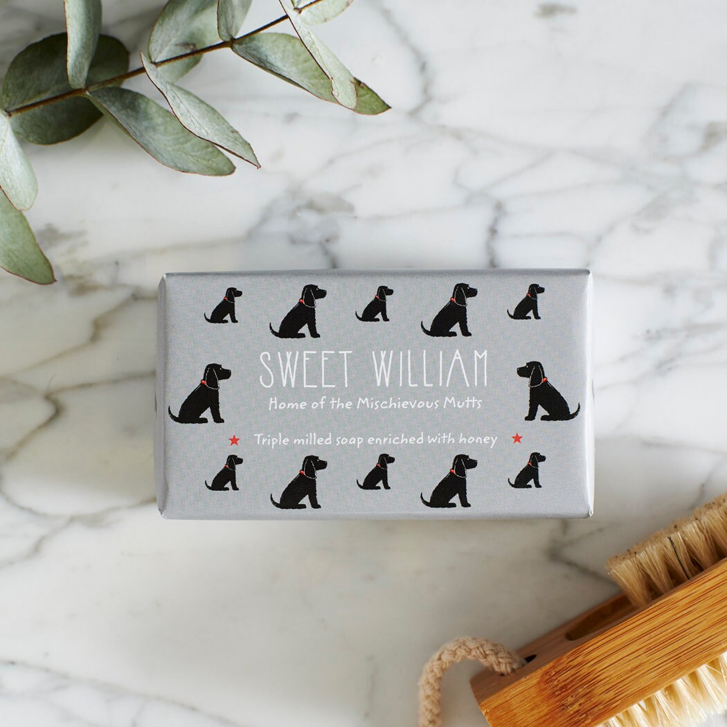Close-up of Black Cocker Spaniel soap packaging — Sweet William triple milled soap enriched with honey, featuring an illustrated Black Cocker Spaniel repeat pattern