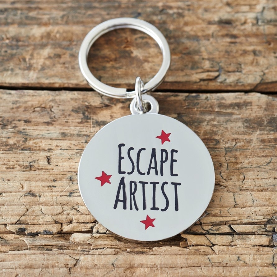 Close-up of 'Escape Artist' dog tag — silver-plated brass with red star design, personalised dog ID tag by Sweet William Designs