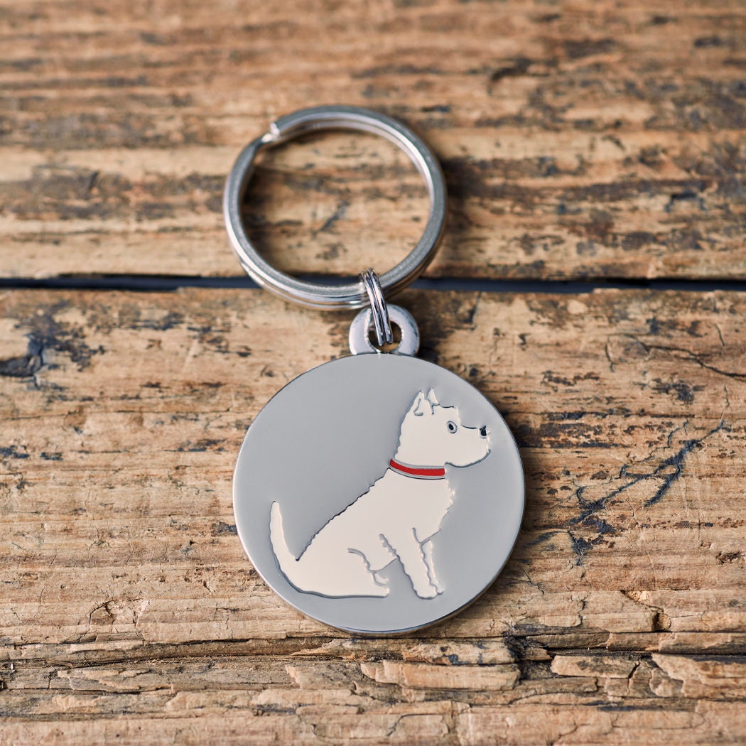 Close-up of West Highland Terrier dog ID tag — silver-plated brass with illustrated Westie design, personalised dog tag by Sweet William Designs