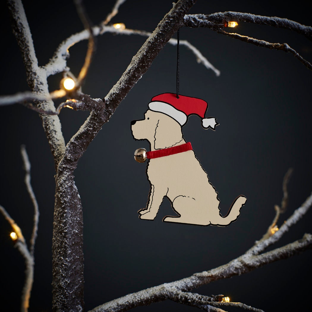 Apricot Cockapoo / Labradoodle Christmas tree decoration hanging on lit winter tree — wooden dog decoration with Father Christmas hat and jingle bell collar by Sweet William Designs