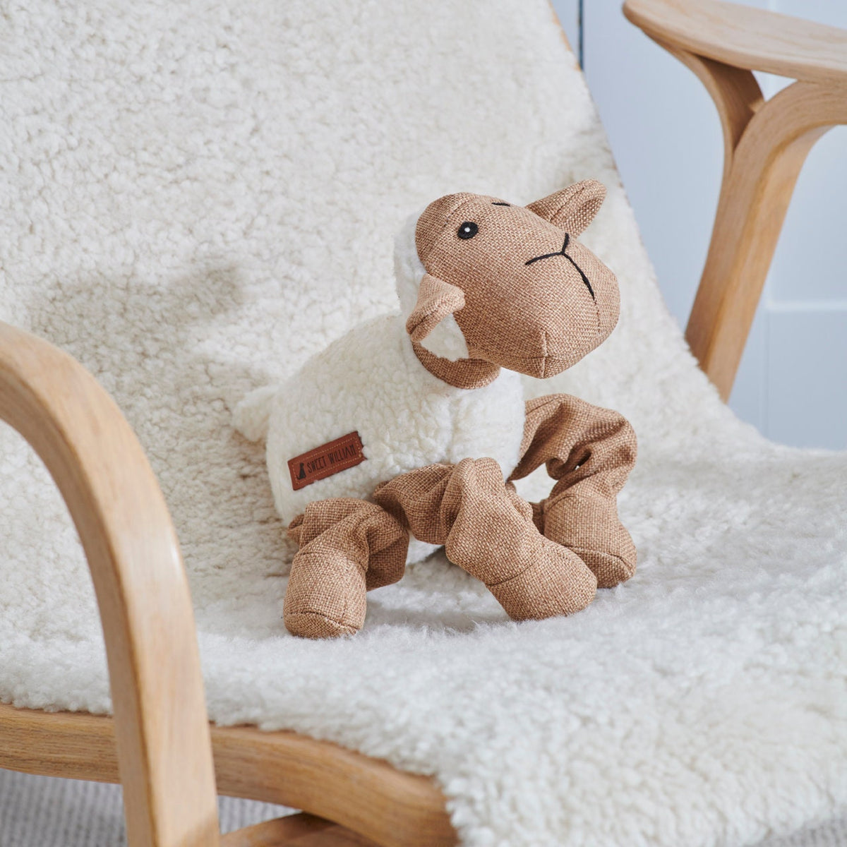 Woolliam the Lamb dog toy on a fluffy chair — soft fabric squeaky toy by Sweet William Designs