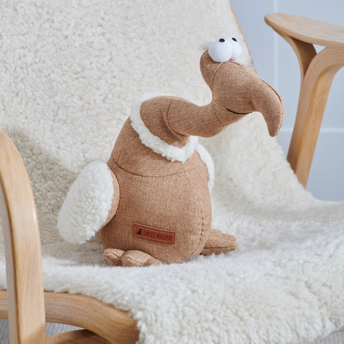 Tarquin the Dodo dog toy on a fluffy chair — fabric squeaky toy by Sweet William Designs