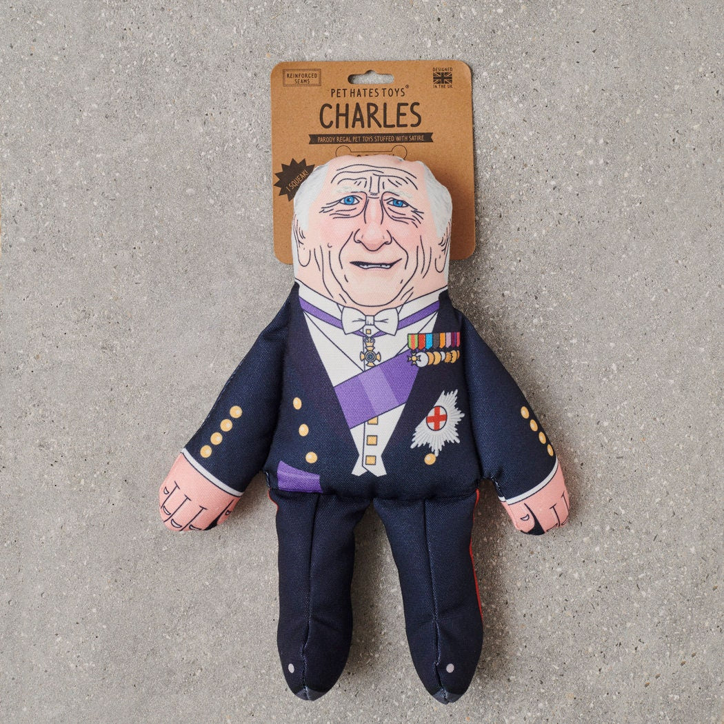 King Charles parody dog toy in navy ceremonial uniform with purple sash and medals — funny squeaky dog toy, royal family gift for dog lovers