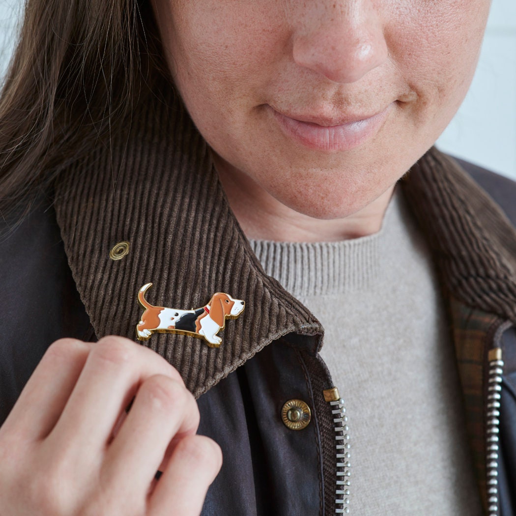 Close-up of Basset Hound enamel pin being attached to a corduroy jacket collar — gold-plated dog lover gift by Sweet William Designs