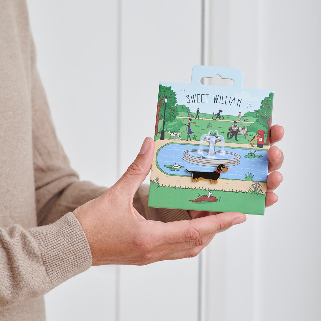 Dachshund enamel dog pin held in hands on illustrated park backing card — gold-plated dog lover gift by Sweet William Designs