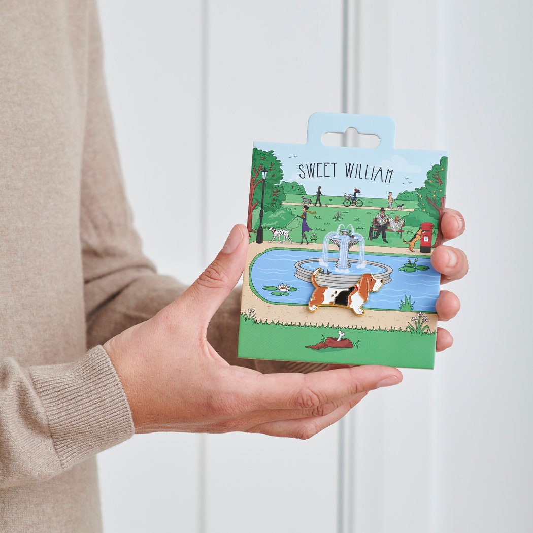 Basset Hound enamel dog pin held in hands on illustrated park backing card — gold-plated dog lover gift by Sweet William Designs