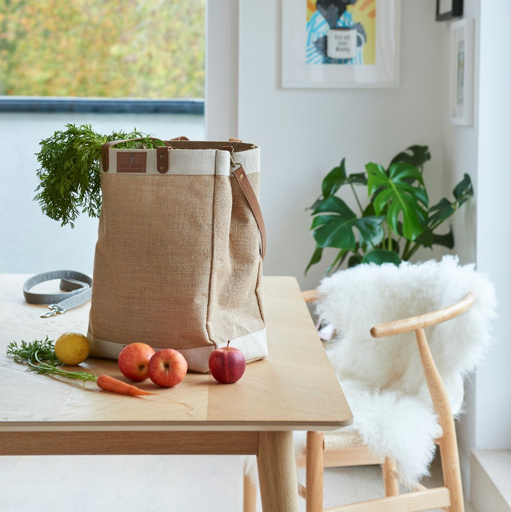 Sweet William jute bag on kitchen table filled with fresh vegetables — large jute tote bag with leather handles