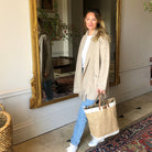 Woman carrying Sweet William jute tote bag through a grand hallway with ornate mirror — stylish large jute bag with leather handles
