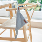 Grey tweed dog bandana threaded onto its matching collar, displayed on a wooden chair with the Sweet William label showing