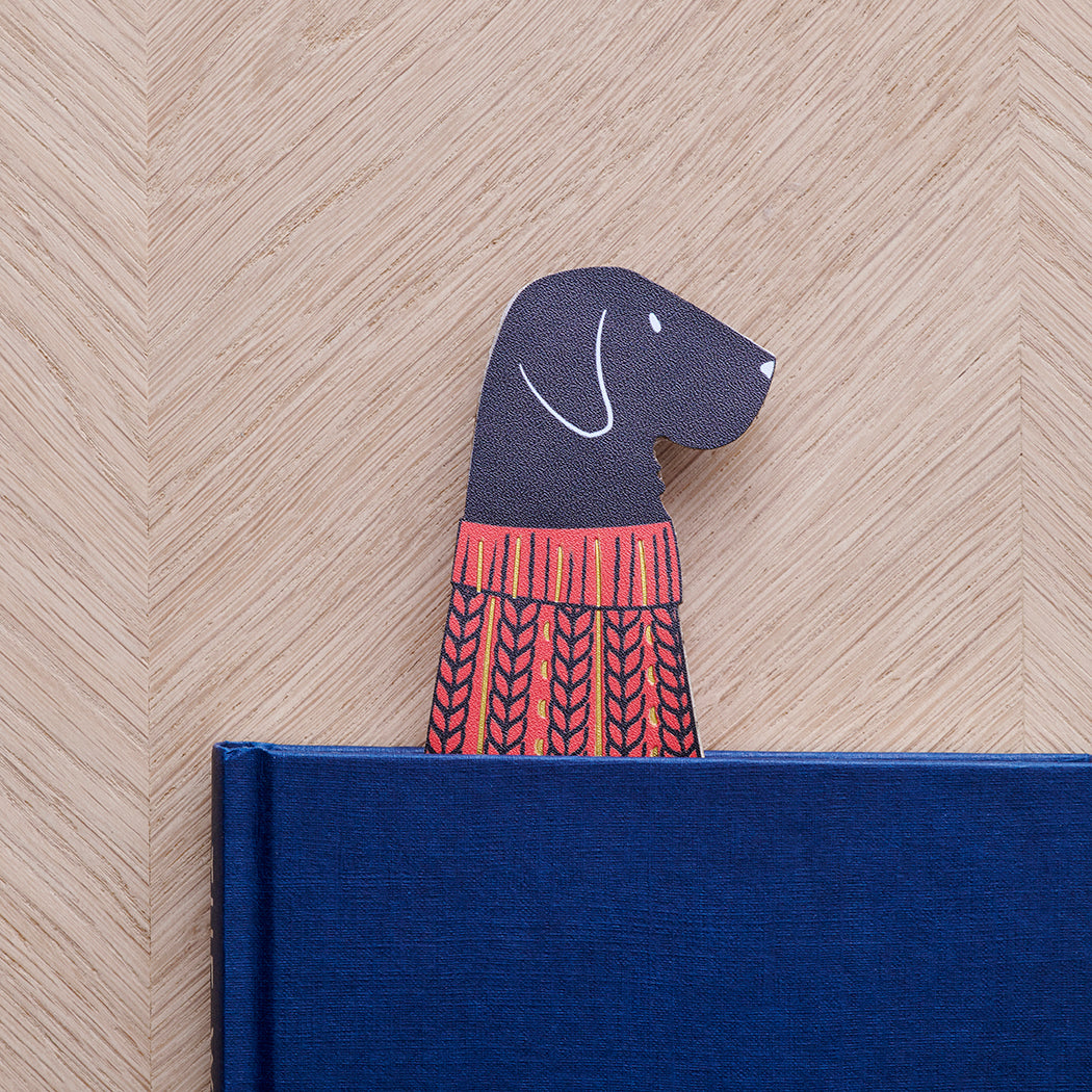 Black Labrador bookmark peeking out of navy book — illustrated dog in red jumper, vegan PU leather bookmark by Sweet William Designs