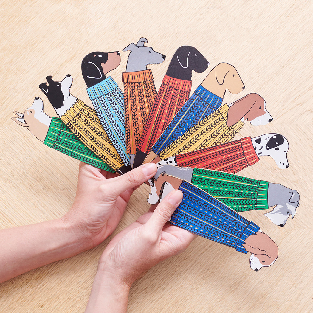 Hand holding fan of illustrated dog breed bookmarks in colourful jumpers — personalised dog lover gifts by Sweet William Designs