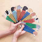 Hand holding fan of illustrated dog breed bookmarks in colourful jumpers — personalised dog lover gifts by Sweet William Designs