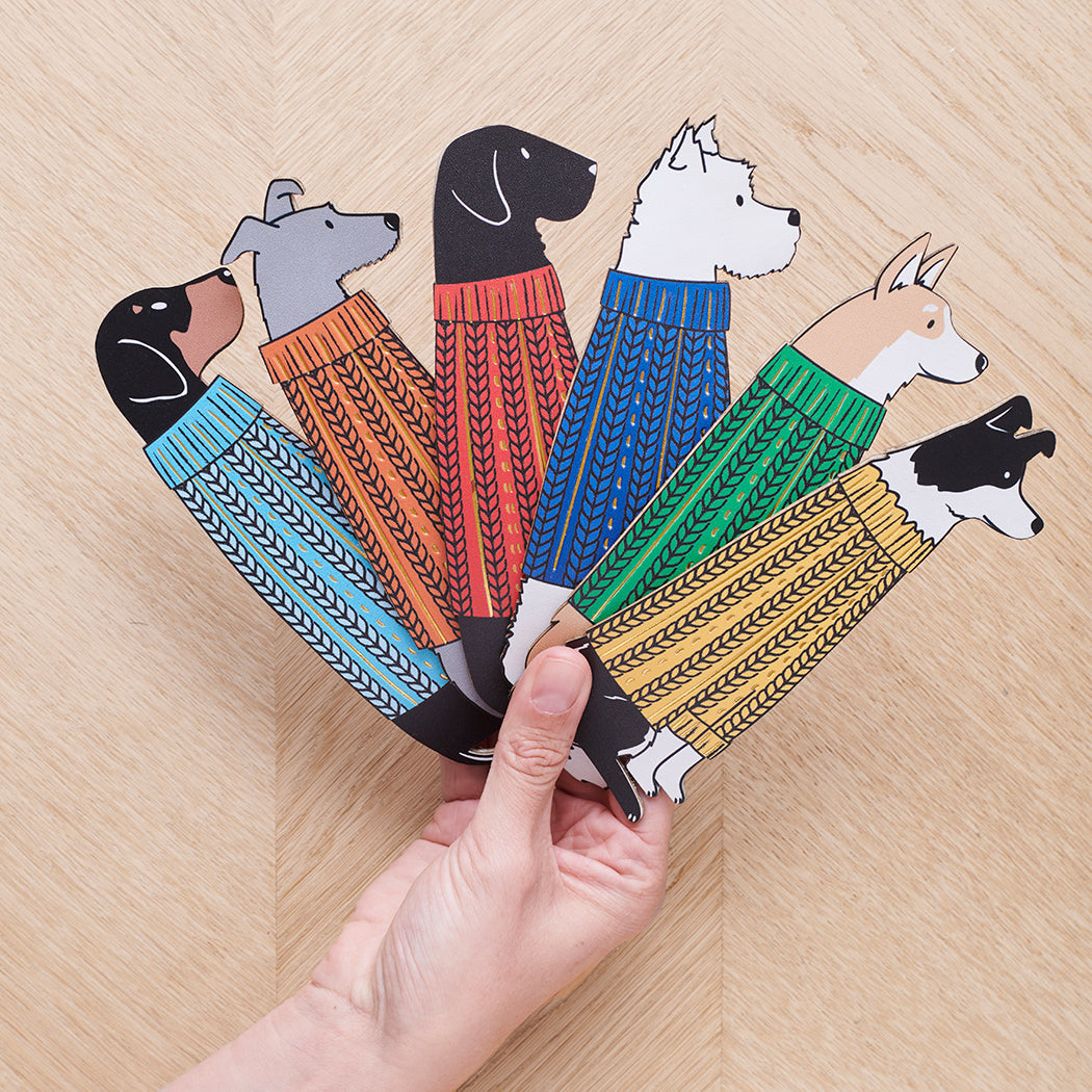 Hand holding a fan of dog bookmarks in colourful knit jumpers — personalised vegan PU leather dog lover gifts by Sweet William Designs
