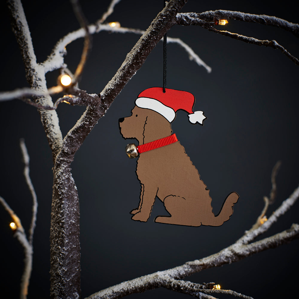 Chocolate Cockapoo / Labradoodle Christmas tree decoration hanging on lit winter tree — wooden dog decoration with Father Christmas hat and jingle bell collar by Sweet William Designs