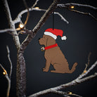 Chocolate Cockapoo / Labradoodle Christmas tree decoration hanging on lit winter tree — wooden dog decoration with Father Christmas hat and jingle bell collar by Sweet William Designs