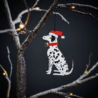 Dalmatian Christmas tree decoration hanging on lit winter tree — wooden dog decoration with Father Christmas hat and jingle bell collar by Sweet William Designs