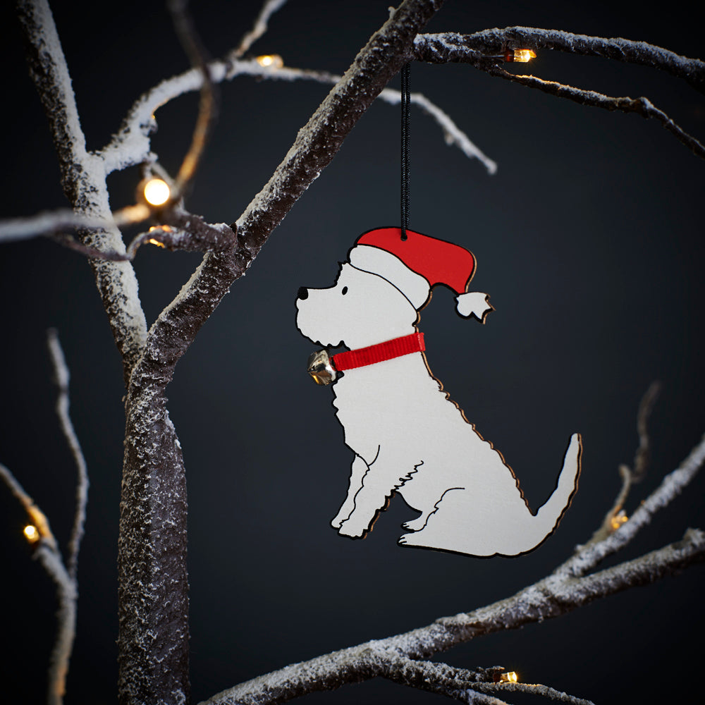 Westie Christmas tree decoration hanging on lit winter tree — wooden dog decoration with Father Christmas hat and jingle bell collar by Sweet William Designs