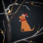 Fox Red Labrador Christmas tree decoration hanging on lit winter tree — wooden dog decoration with Father Christmas hat and jingle bell collar by Sweet William Designs