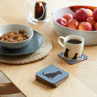 Black Labrador coasters stacked on a breakfast table beside a matching mug