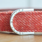 Close-up of the branded D-ring on an orange tweed dog collar
