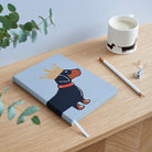 Dachshund notebook on wooden desk styled with matching Dachshund mug — illustrated sausage dog gift by Sweet William Designs